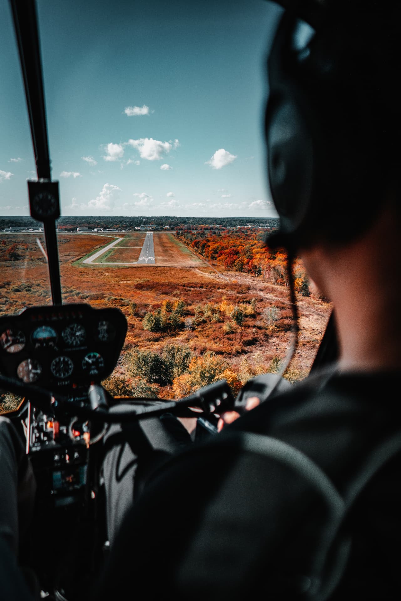 View over the pilot's shoulder on approach with fall color below